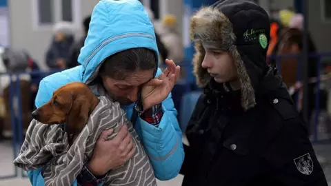 Odessa's owner, wearing a blue jacket, holds Odessa in a blanket with her son comforting her
